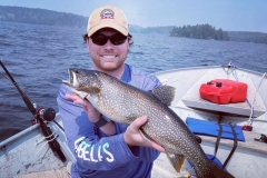 Angler Holding Lake Trout Beside Boat