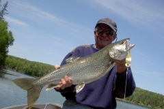 Angler Holding Trout With Trees in Background