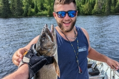 Smiling Angler Holding Trout With Forest Behind