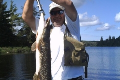 Angler Displaying Large Pike Beside Calm Bay