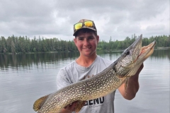 Angler Holding Lean Pike Beside Forest Edge