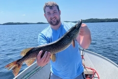 Angler Displaying Pike Under Bright Sunny Sky