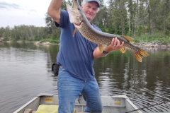 Angler Raising Pike in Evening Reflections