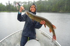 Woman Hoisting Long Pike on Blue Lake