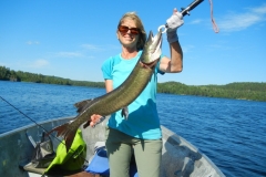 Woman Holding Long Pike in Clear Blue Water