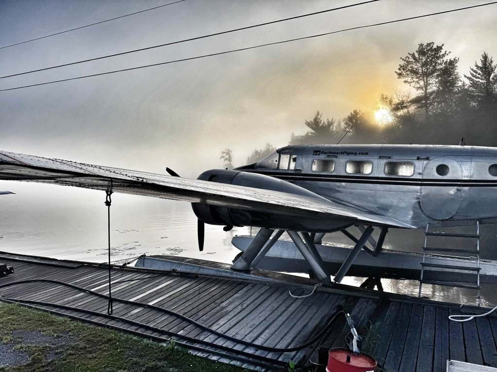 Beech 18 floatplane on the dock at the Northwest Flying airbase in Nestor Falls, Ontario, in fog at sunrise, July 2026