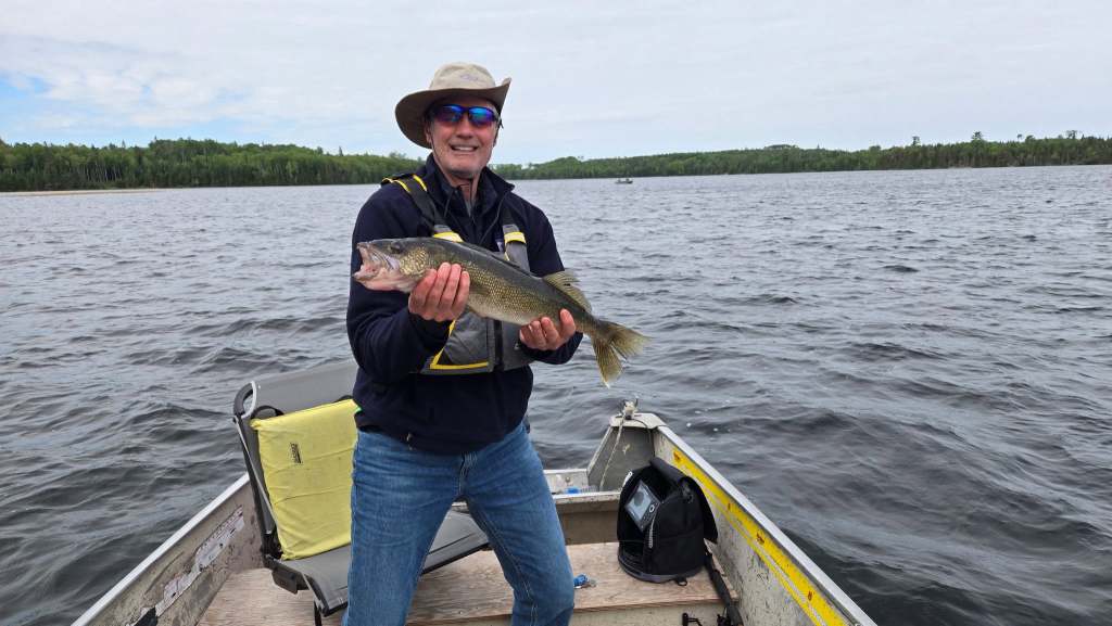 Angler in a boat holding a walleye caught on Loonhaunt Lake, a Northwest Flying fly-in outpost lake near Nestor Falls, Ontario, June 2026